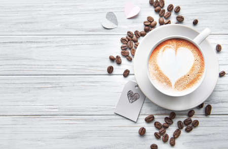 A cup of coffee with heart pattern  on a white wooden backgroundの写真素材