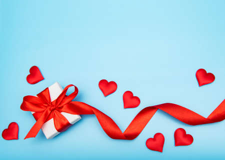 Holiday background with decorative gift box, red bow and silk  hearts. Valentine conceptの写真素材