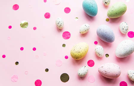 Easter holiday background. Colorful Easter eggs on a pastel pink background. Flat lay, top view.