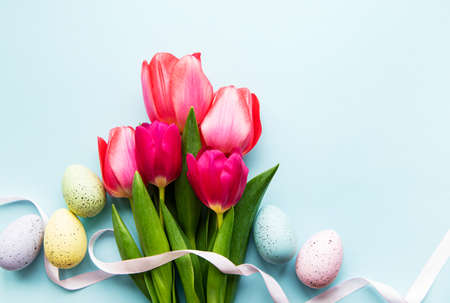 Spring tulips and Easter eggs  on a pastel blue  background