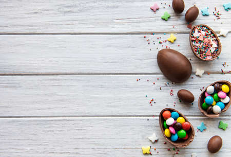 Easter composition with colorful and chocolate eggs on white wooden background, space for text. Top...