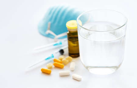 Medications pills drug, mask and glass of water. Flu outbreak and coronavirus or influenza. Medicine conceptの写真素材