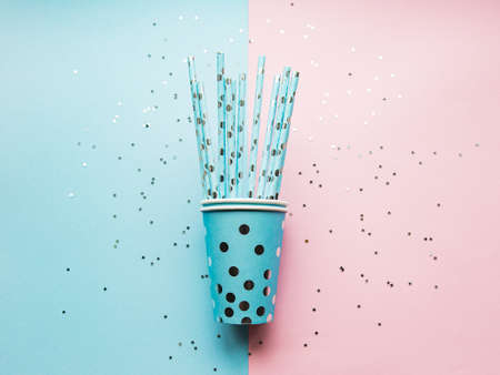 Birthday party caps,  paper straws and confetti  on pink and blue backgroundの写真素材