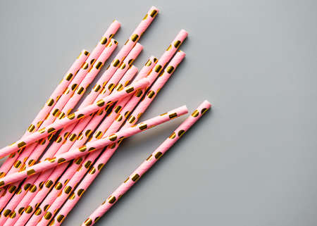 Drinking dotted straws for party  on grey  background with copy space. Top view of colorful paper disposable eco-friendly straws for summer cocktails.の写真素材