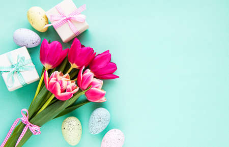 Spring tulip flowers, Easter eggs and gift box  on pastel green background. Greeting for Easter. ...