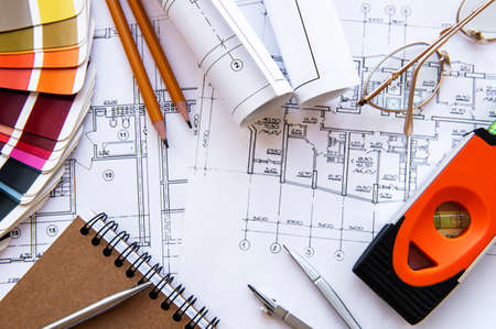 Architect workplace top view. Architectural project, blueprints, blueprint rolls on table. Construction background. Engineering tools. Copy spaceの写真素材