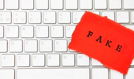 Word Fake written on torn paper on a computer keyboard