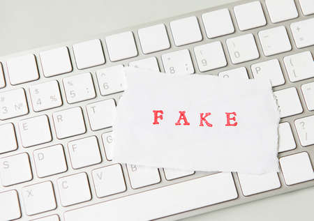 Word Fake written on torn paper on a computer keyboard