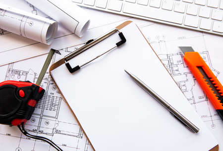 Architect workplace top view. Architectural project, blueprints, blueprint rolls on table. Construction background. Engineering tools. Copy spaceの写真素材