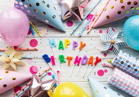 Text Happy Birthday by candle  letters with birthday asseccories, candles and confetti  on white wooden  background. Top view, flat lay. の写真素材