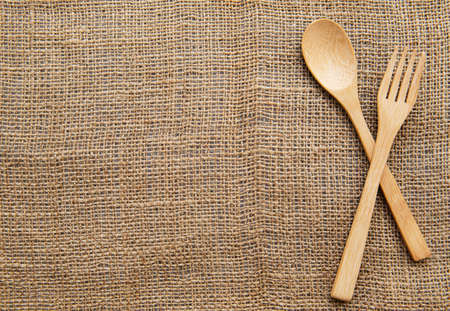Wooden spoon and  fork on sackcloth backgrounds. Top viewの写真素材
