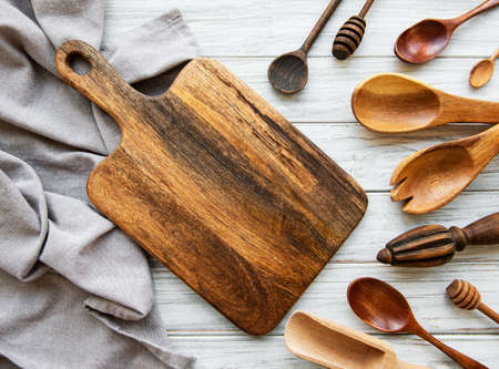 Old vintage kitchen utensils. Wooden spoons,  cutting board, napkin. Over white wooden table. Top viewの写真素材