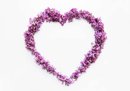 Frame of branches and flowers of lilac on a table in the shape of a heart,  top viev, flat lay, copy...