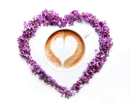 Lilac flowers on a white background in the shape of a heart,  top view on a cup of coffeeの写真素材