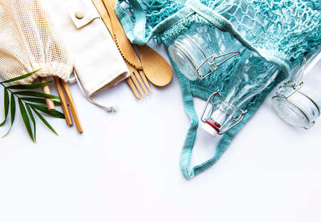 Cotton bags, net bag with reusable  glass jars, bamboo and wooden cutlery on white background. Zero...