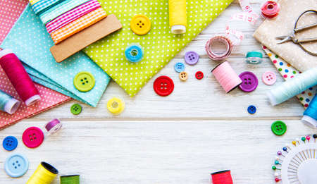 Sewing accessories and fabric on a white background. Sewing threads, needles, pins, fabric, buttons...