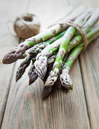 Bundle of fresh green asparagus on a rustic wooden table , top viewの写真素材