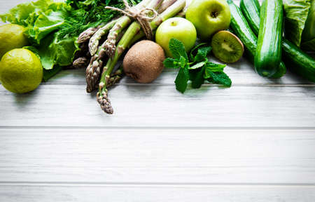 Healthy vegetarian food concept background, fresh green food selection for detox diet,  apple, cucumber, asparagus, avocado, lime,  salad  top view on a white wooden  backgroundの写真素材