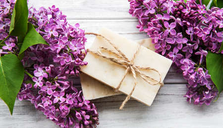 Natural soap and lilac flowers on a white wooden background, top viewの写真素材