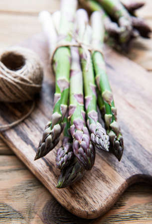 Bundle of fresh green asparagus on a rustic wooden table, top viewの写真素材