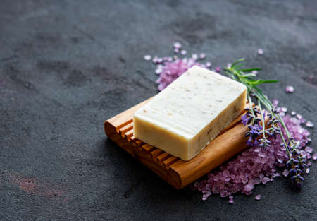 Organic soap and a bouquet of fresh lavender flowers on dark concrete background