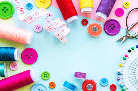 Sewing accessories on a blue pastel background. Sewing threads, needles, pins, buttons and sewing centimeter. Top view, flat lay.の写真素材