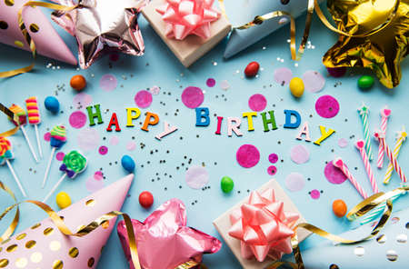 Text Happy Birthday by wooden letters with birthday asseccories, candles and confetti on blue backgroundの写真素材