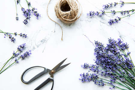 Lavender flowers, scissors and rope on a white marble background