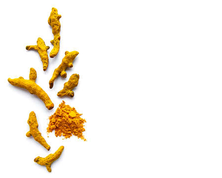 Yellow turmeric powder and dry roots on white background.