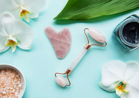 Jade roller for face massage. Pink gua sha facial massager tools. Anti age, lifting and toning treatmentの写真素材