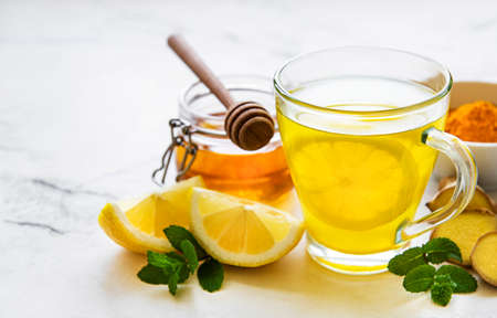 Energy tonic drink with turmeric, ginger, lemon and honey on a white wooden backgroundの写真素材