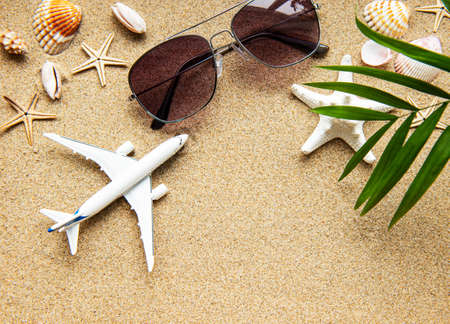 Top view of traveler background on tropical sand, shells and airplane. Background for summer holiday vacation travel trip. Flat lay, copy space