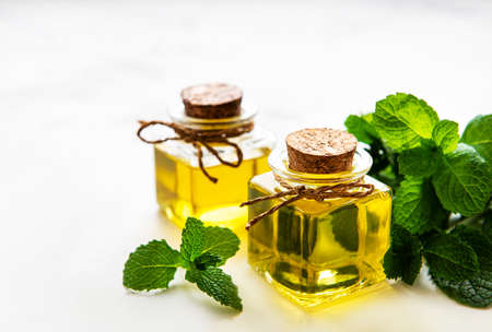 Organic essential mint oil with green leaves on a white backgroundの写真素材