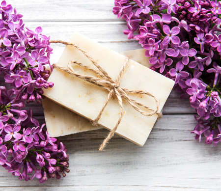 Natural soap and lilac flowers on a white wooden background, top viewの写真素材
