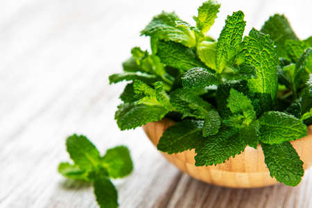 Bowl with a bunch of fresh mint on the old wooden table. The concept of healthy eating.