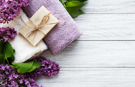 Spa towels and soap and lolac flowers on a white wooden tableの写真素材