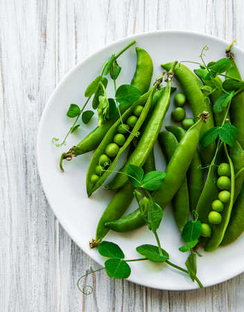 Green peas in a plate on a white wooden background. View from above.の写真素材