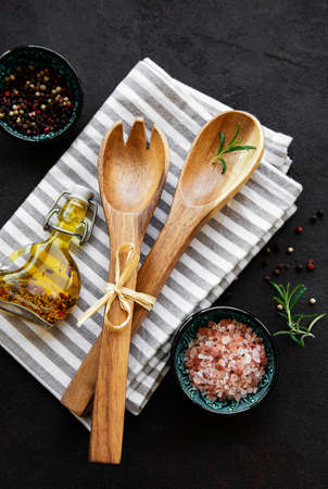 Old vintage kitchen utensils. Wooden spoons, cutting board, napkin and spices over black background. Top viewの写真素材