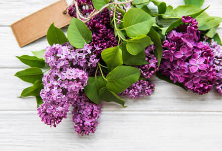 Lilac in flat style on white wooden background. Beautiful spring. Overhead view. Flat lay, top....