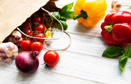 Healthy food background. Healthy food in paper bag, vegetables on a white wooden backgroundの写真素材