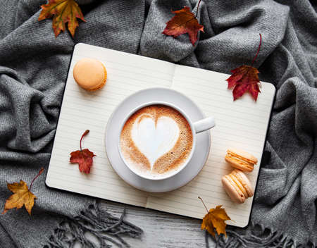 Maple leaves, notebook, coffee cup and scarf. Autumn or Winter concept. Flat lay, top viewの写真素材