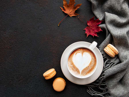 Cup of coffee and dry leaves on black concrete background. Flat lay, top view, copy spaceの写真素材
