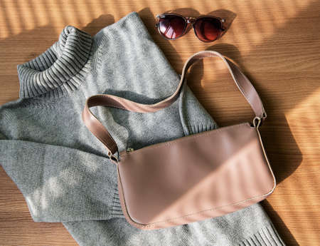 Small beige leather bag and gray women's sweater