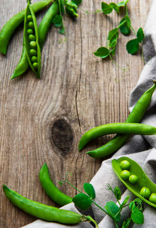 Pods of green peas with pea leaves on a old wooden background. Organic food.の写真素材