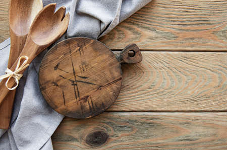 Old vintage kitchen utensils. Wooden spoons, cutting board, napkin over white wooden table. Top viewの写真素材