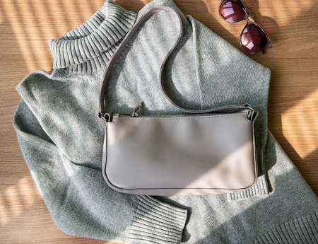 Small beige leather bag and gray women's sweater