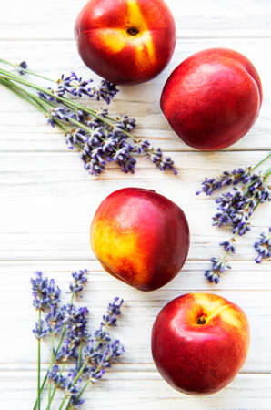 Nectarines and flowers of lavender on a white wooden backgroundの写真素材