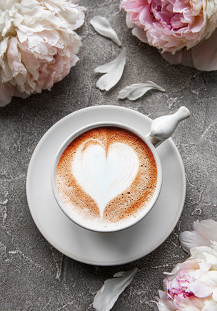 Pink peony and cup of coffee in beautiful style on gray concrete background. Floral background. Top view.の写真素材