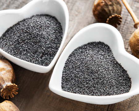 Poppy seeds in heart shaped bowls on the wooden backgroundの写真素材