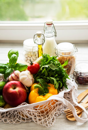 Zero waste concept. Eco bag with fruits and vegetables, glass jars with beans, pasta, milk and oil. Eco-shopping friendly and cooking concept, flat layの写真素材